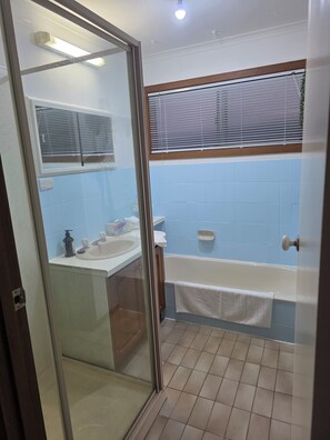 Un baño con cabina de ducha de vidrio, un lavamanos blanco, una bañera y paredes con azulejos azules.