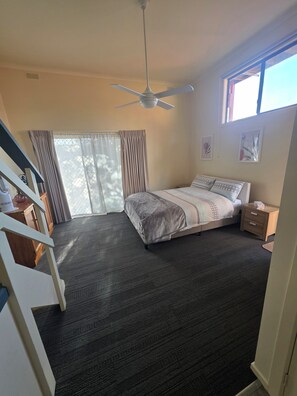 A bedroom with a bed, a ceiling fan, a window, and a staircase. - Seaside location close to all amenities (San Remo)