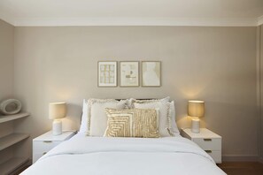 A bedroom with a bed, two bedside lamps, a nightstand, and three framed artworks on the wall. - First Act on Fulham Road (Greater London)