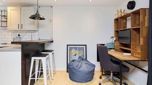 A compact kitchen with white cabinets, a wooden countertop, and a hanging light fixture. - Meet Me in Willesden Green (London)