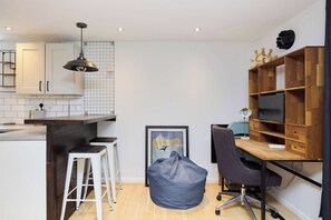 Eine kleine Küche mit weißen Schränken, einer Holz Arbeitsplatte und einer Pendelleuchte.