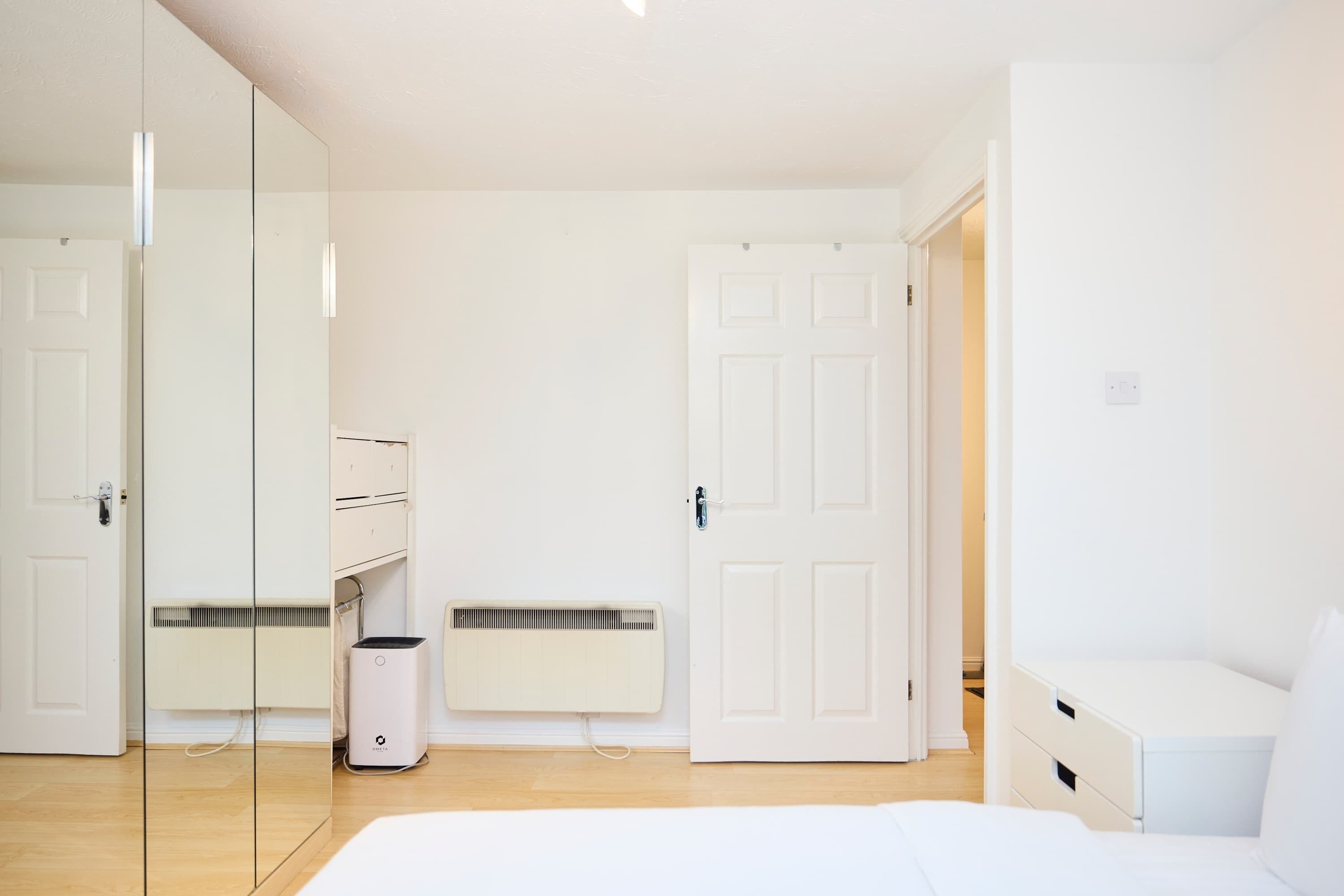 Un dormitorio minimalista con una cama, un armario, un radiador y una puerta.