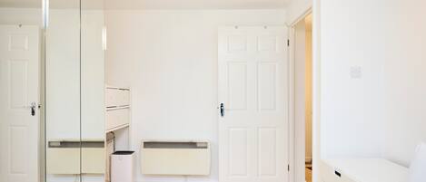 Un dormitorio minimalista con una cama, un armario, un radiador y una puerta.