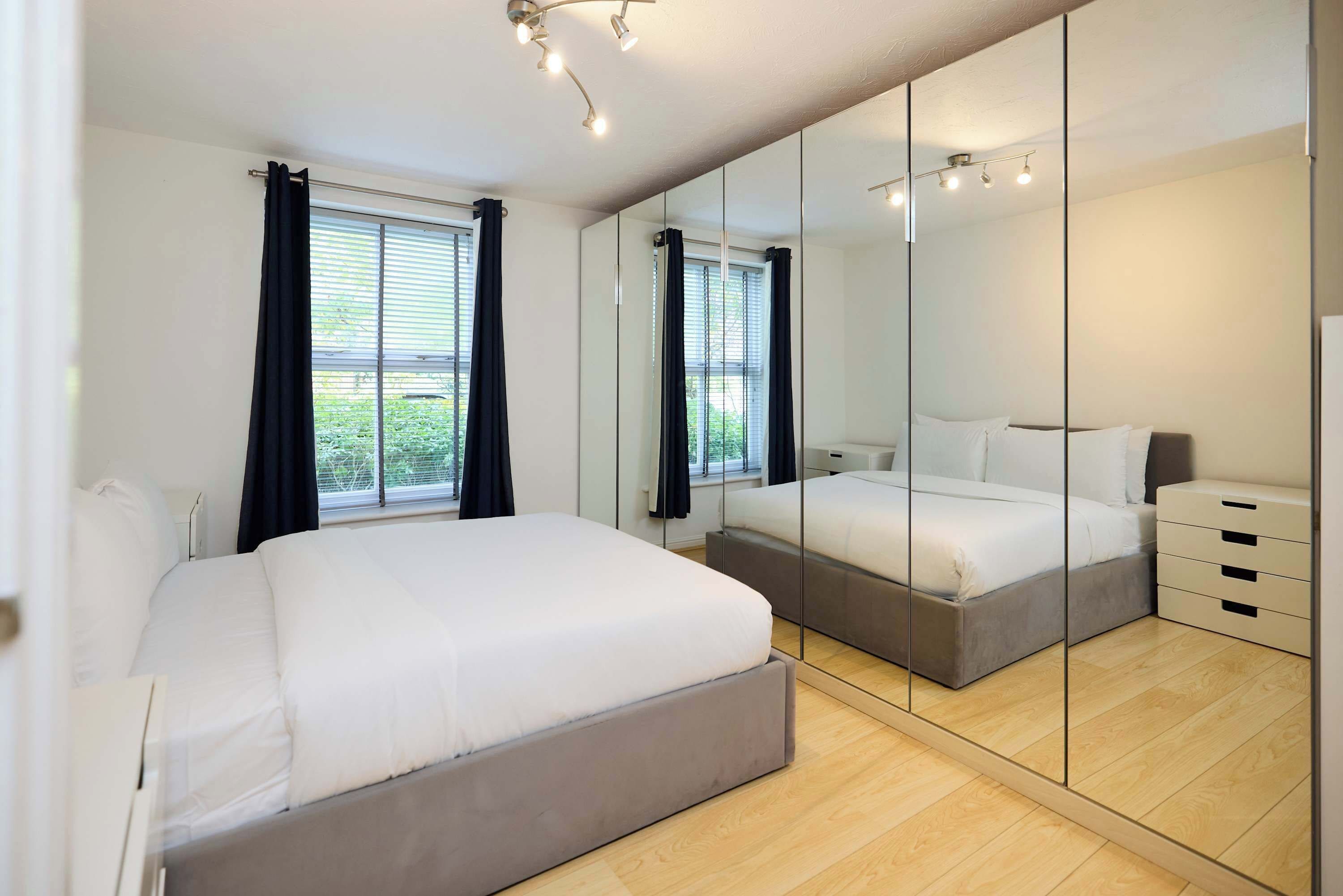 Un dormitorio moderno con una cama grande, un armario y un espejo.