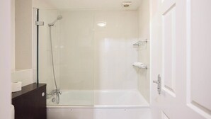 A bathroom with a glass-enclosed shower, a white bathtub, and a dark wooden vanity. - Meet Me in Willesden Green (London)