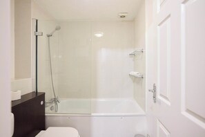 Ein Badezimmer mit einer gläsernen Duschkabine, einer weißen Badewanne und einem dunklen Holzwaschtisch.