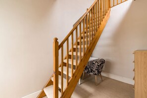 A wooden staircase with carpeted steps leading to a landing. - Brick & Beam on Tabard (London)