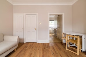 A room with a wooden floor, a sofa, a small table, and a chair. - Brick & Beam on Tabard (London)