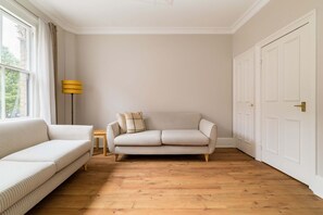Ein Zimmer mit einer Couch, einem kleinen Tisch und einer Lampe.