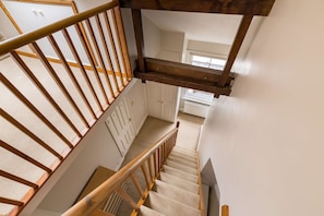 A wooden staircase with a handrail leading to a landing. - Brick & Beam on Tabard (London)