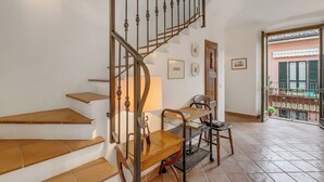 A staircase with a wooden finish and metal balusters, a small wooden table with a lamp, and a metal shelf unit. - Apt. Annamaria: Family-Friendly 2BR Central Base for Trips, Laveno Mombello, Italy (Laveno Mombello)