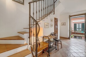 Eine Treppe mit Holzbeschichtung und Metallgeländern, ein kleiner Holztisch mit Lampe sowie ein Metallregal.