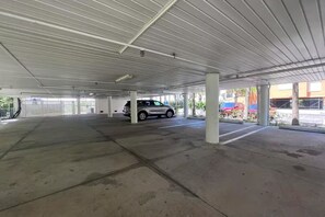 Garagem de estacionamento vazia, com pisos de concreto e pilares brancos.