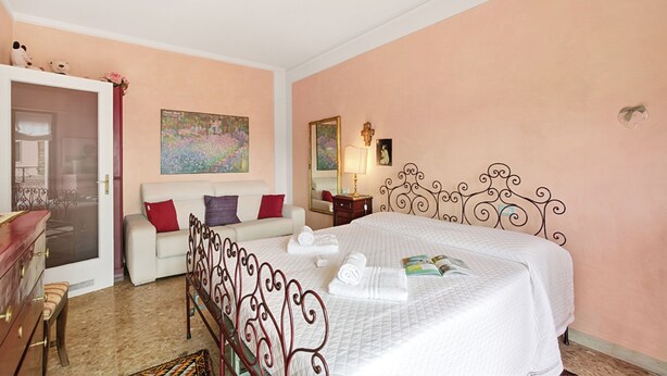 A bedroom with a bed, a white sofa, a dresser, and a door leading to another room. - Roma 62 Lake View,Terrace & Private Park, Toscolano Maderno, Italy (Toscolano Maderno)