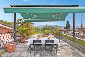 Eine Terrasse mit Frühstückstisch, umgeben von Pflanzen in Töpfen und mit Blick auf eine reizvolle Landschaft.