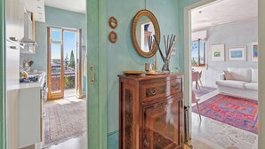 A room with a wooden cabinet, a mirror, and a dining area with a red patterned rug. - Roma 62 Lake View,Terrace & Private Park, Toscolano Maderno, Italy (Toscolano Maderno)