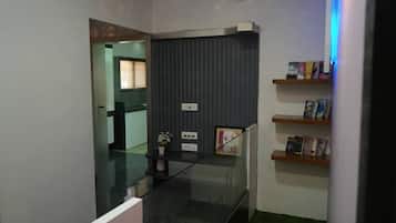 A modern interior with a glass staircase, a dark wall unit with books, and a green carpeted area.
