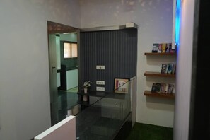 Ein modernes Interieur mit einer Glasstiege, einer dunklen Wandschranke mit Büchern und einem grünen Teppichbereich.