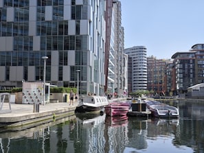 Ein modernes Gebäude mit Glasfassade, eine Uferpromenade und ein Boot, das am Wasserrand liegt.