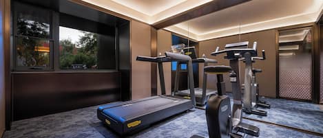 Un gimnasio moderno con cintas de correr, bicicletas estáticas y una máquina de remo.