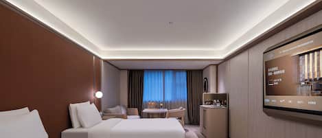 Quarto de hotel com duas camas, uma escrivaninha, uma cadeira, uma televisão e um minibar.