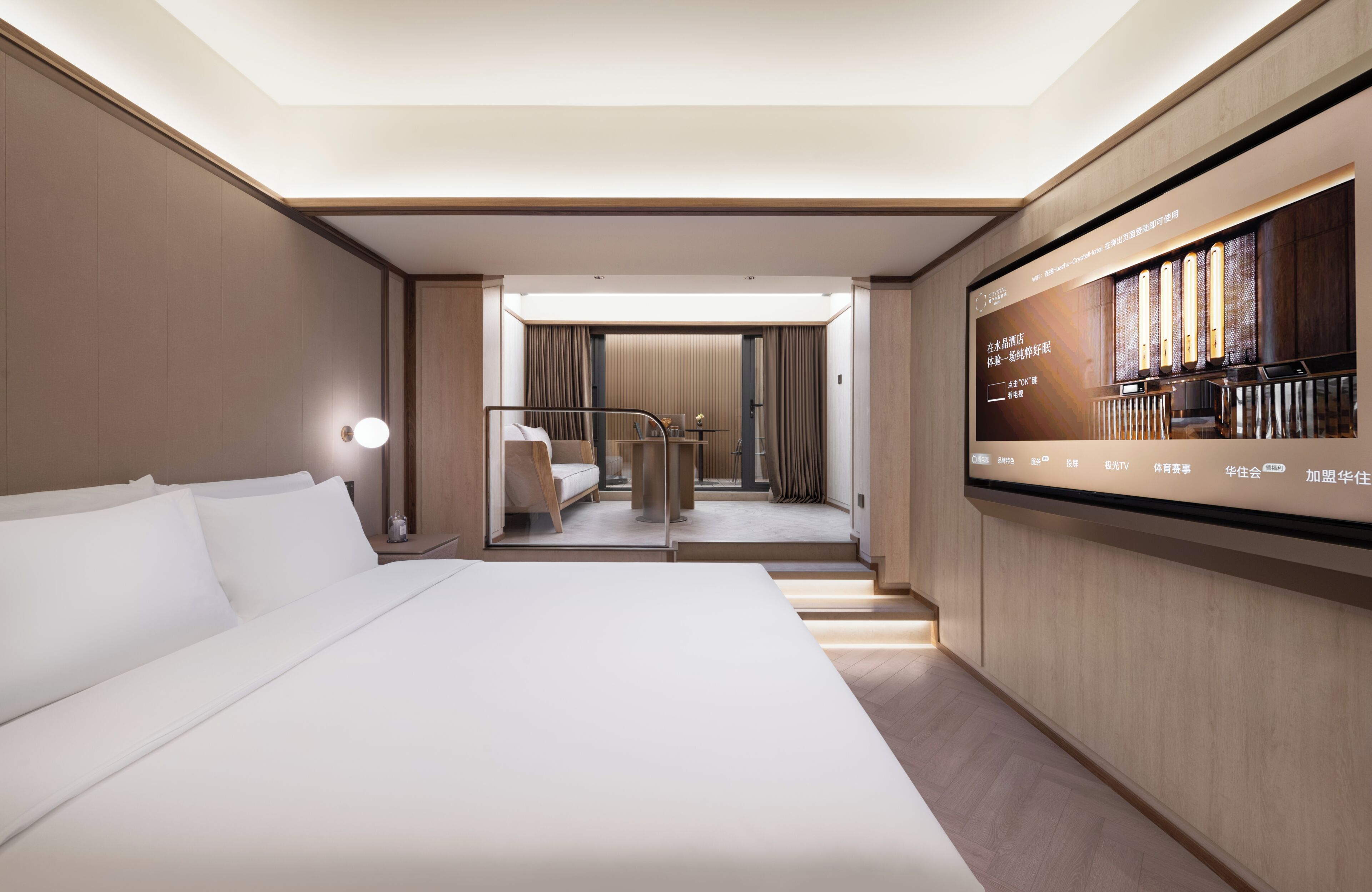 A hotel room with a large bed, a TV mounted on the wall, and a view of the hotel's interior.