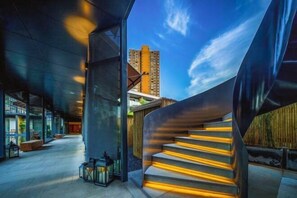 A modern building with a curved staircase and a view of a tall building in the background. - MEHOOD LESTIE Hotel (Nanchang Tengwang Pavilion) (Nanchang)