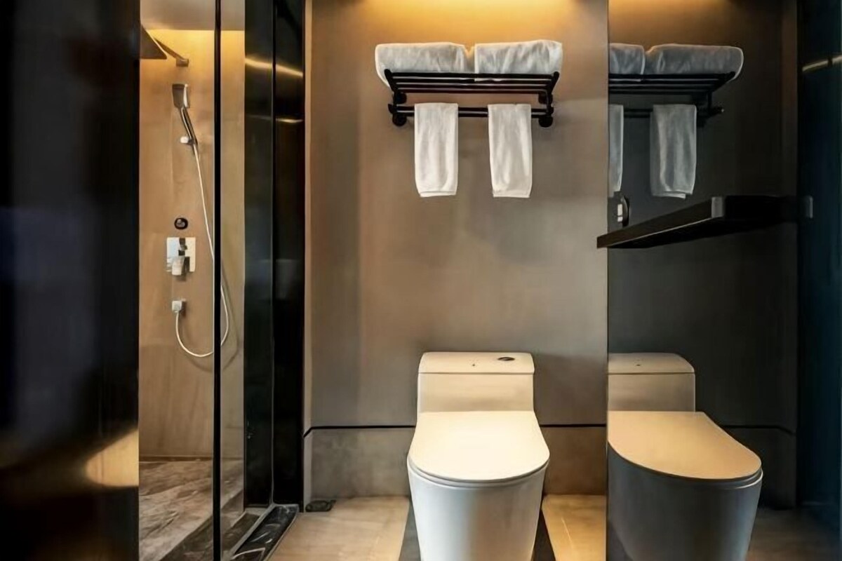 A modern bathroom with two toilets, a shower, and a towel rack.