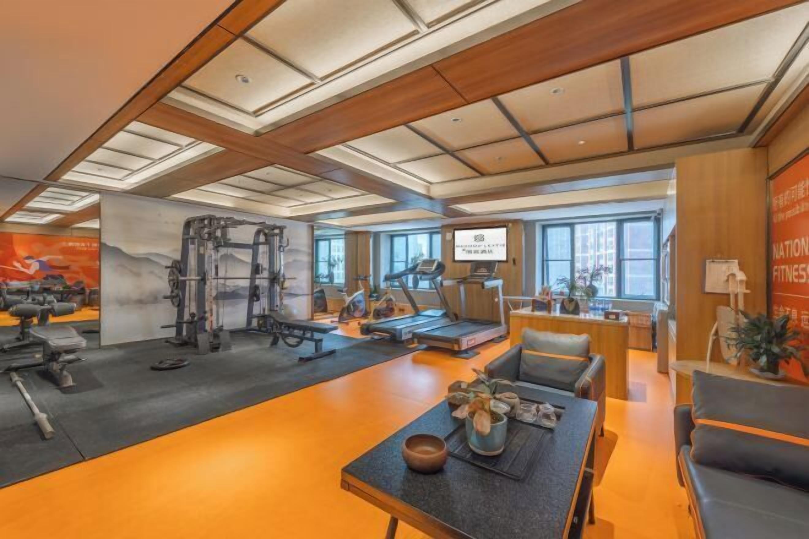 Una palestra con attrezzature per esercizi, una reception e un'area relax con tavolo e sedie.
