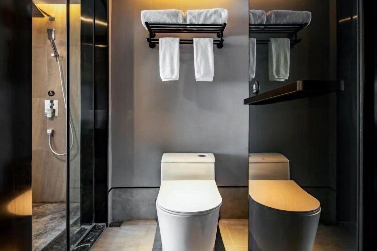 A modern bathroom with a glass-enclosed shower, a toilet, and a towel rack.