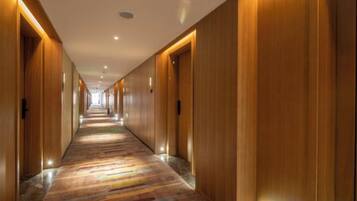 A long hallway with wooden doors and a patterned carpet.