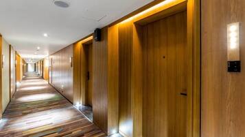 Un pasillo de hotel con puertas de madera y una alfombra estampada.