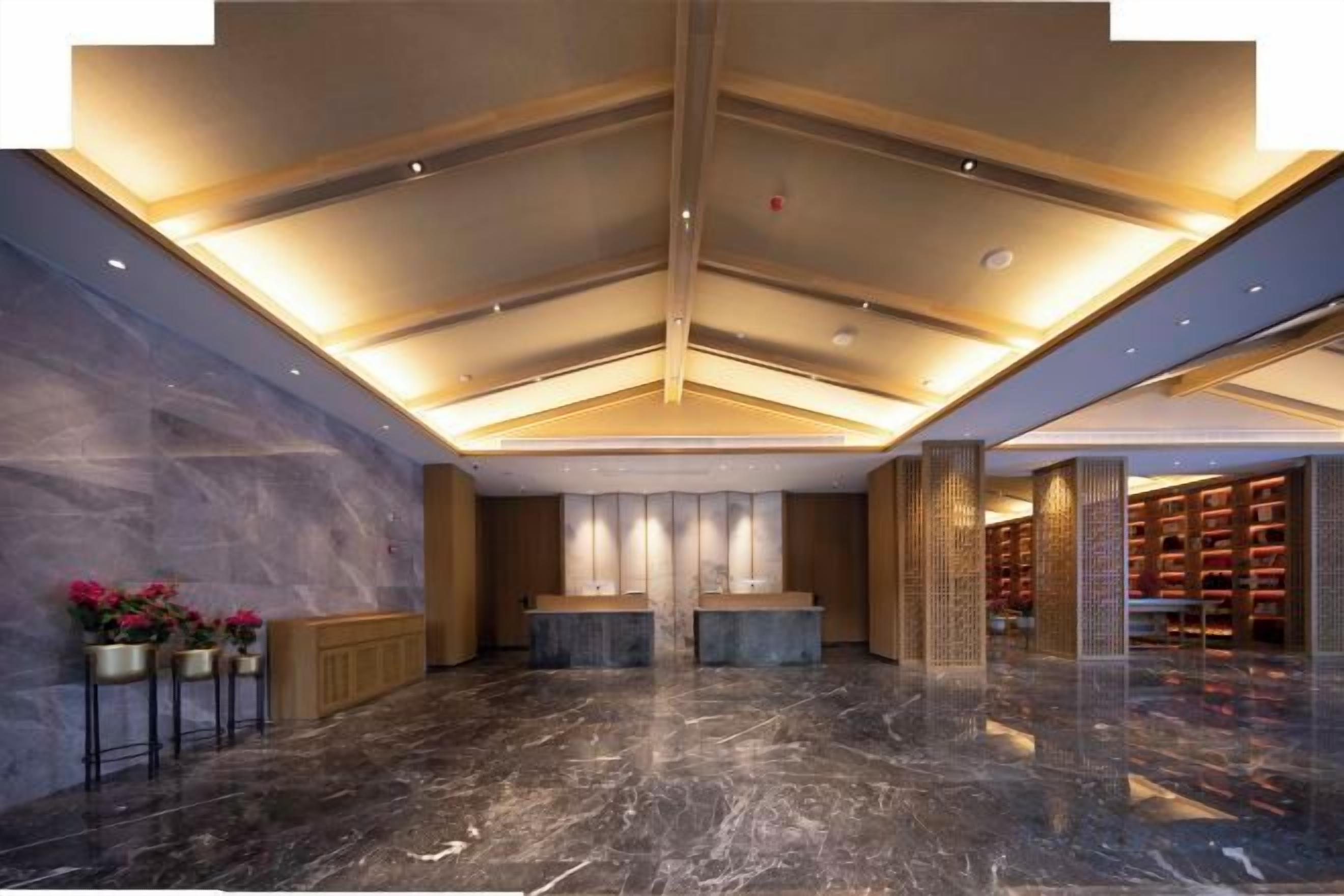 A hotel lobby with a marble floor, a reception desk, and a bookshelf area.