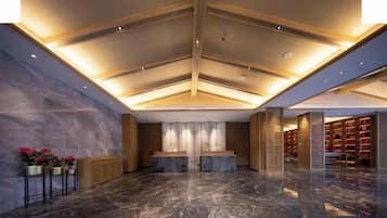 A hotel lobby with a marble floor, a reception desk, and a bookshelf area.