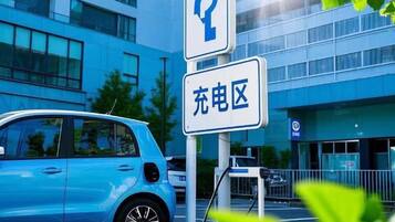 Un estacionamiento con un auto azul y un cartel que indica zona de carga.