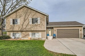 Ein zweistöckiges Haus mit Garage, einer Veranda mit Stühlen und einem gepflegten Rasen.