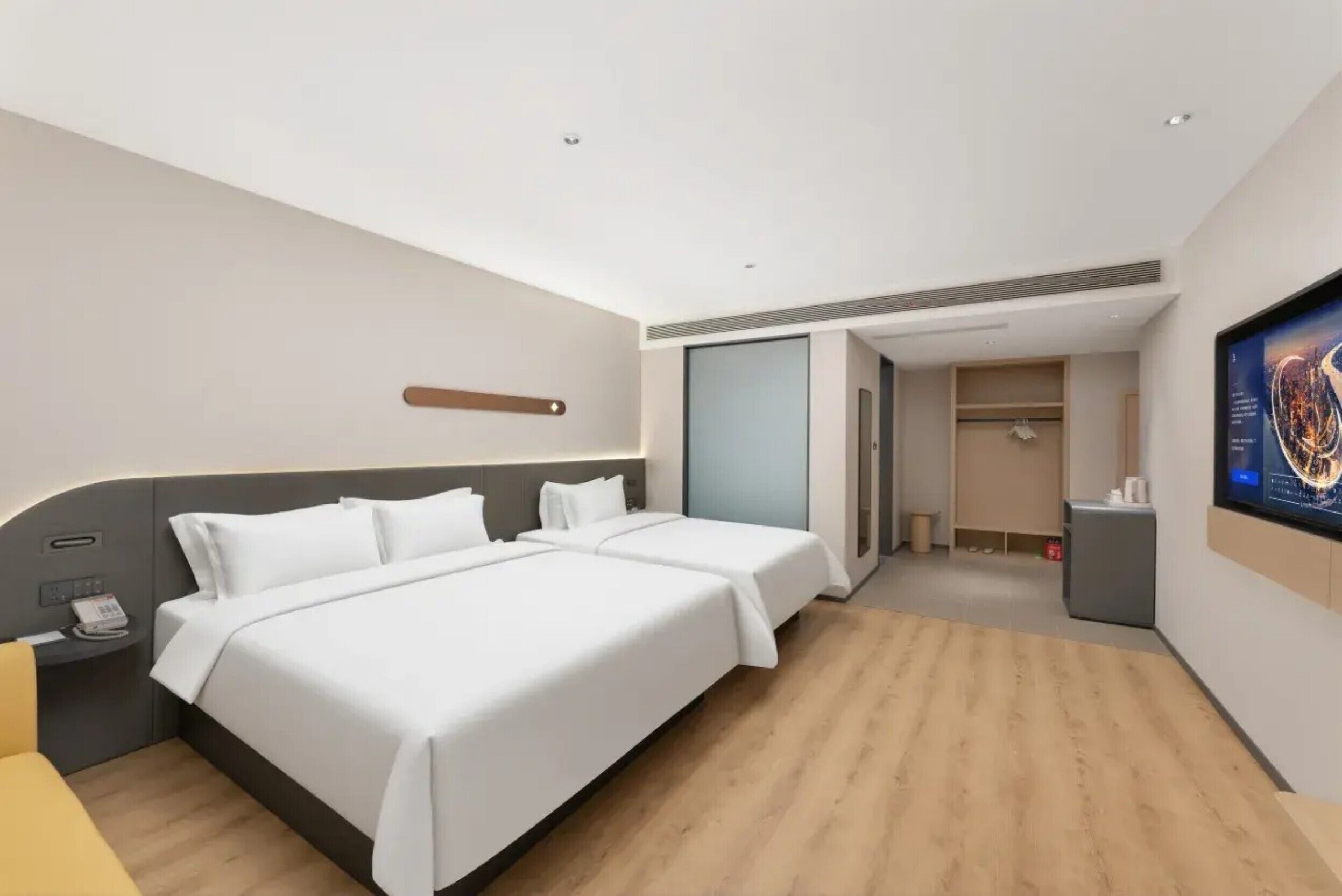 Habitación de hotel con dos camas, un escritorio, una silla, un televisor y un armario.