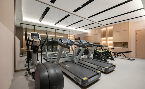 Un gimnasio moderno con cintas de correr, una bicicleta estática y una máquina de remo.