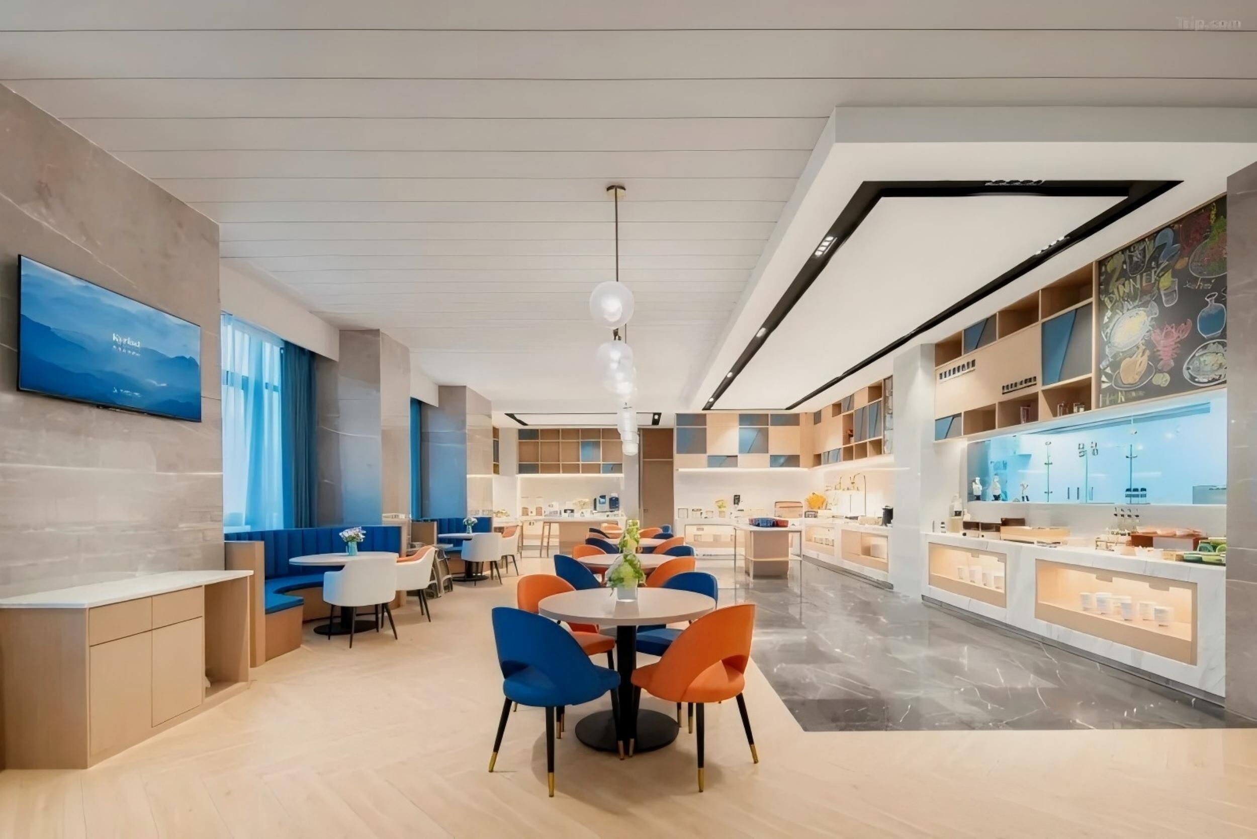 A modern dining area with round tables and chairs, a television mounted on the wall, and a ceiling with recessed lighting.