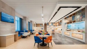 A modern dining area with round tables and chairs, a television mounted on the wall, and a ceiling with recessed lighting. - Jinjiang Inn (Wuhan)