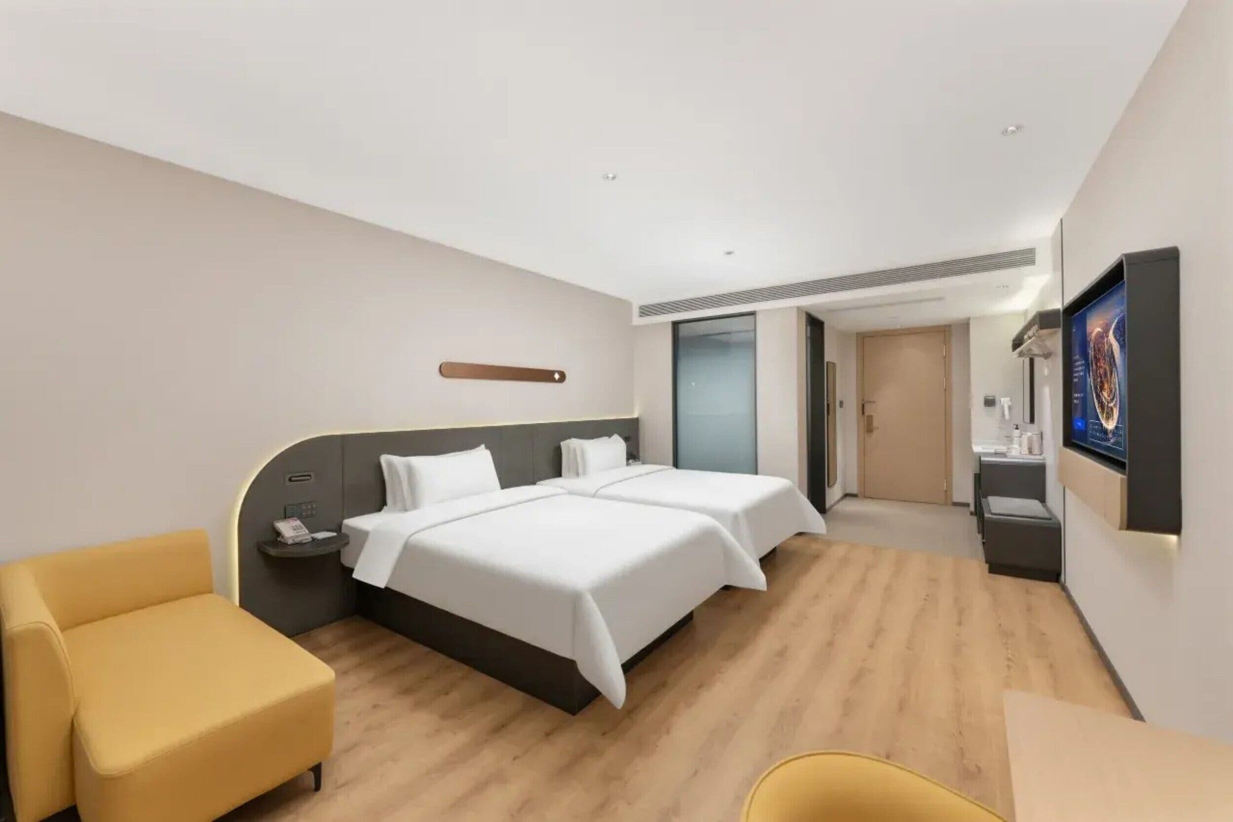 Habitación de hotel con dos camas, un escritorio, una silla, un televisor y un baño.