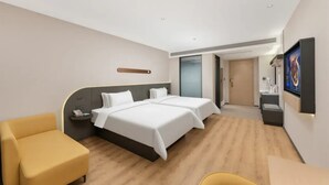 Hotellihuone, jossa on kaksi sänkyä, työpöytä, tuoli, televisio ja kylpyhuone.