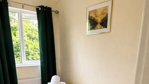 A bedroom with a bed, a window with curtains, a radiator, and a painting on the wall. -  Stylish 3BR | Sleeps 5 | Long Stay welcome (Mansfield)