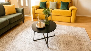 A living room with a yellow sofa, a green sofa, a round coffee table, and a patterned rug. -  Stylish 3BR | Sleeps 5 | Long Stay welcome (Mansfield)
