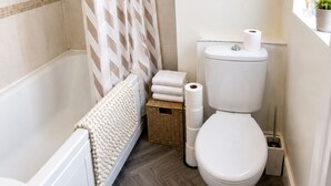 A bathroom with a bathtub, toilet, and shower curtain. -  Stylish 3BR | Sleeps 5 | Long Stay welcome (Mansfield)