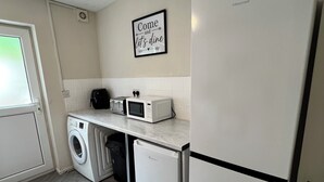 Une cuisine compacte équipée d’un lave-linge, d’un four à micro-ondes et d’un réfrigérateur.