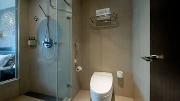 A bathroom with a glass-enclosed shower, a toilet, and a small shelf with toiletries.