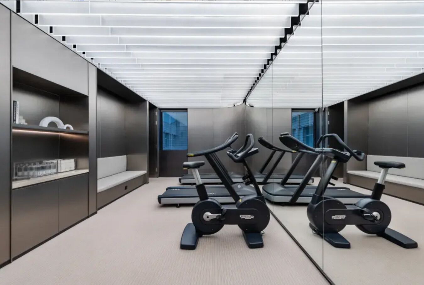 A modern gym with treadmills, a weight bench, and a mirrored wall.