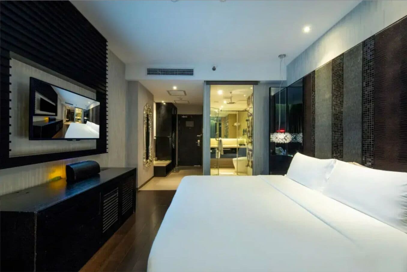 Una habitación de hotel moderna con una cama grande, un televisor de pantalla plana en la pared y un vestidor.
