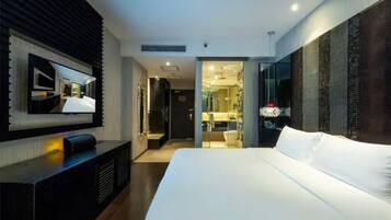 Una habitación de hotel moderna con una cama grande, un televisor de pantalla plana en la pared y un vestidor.